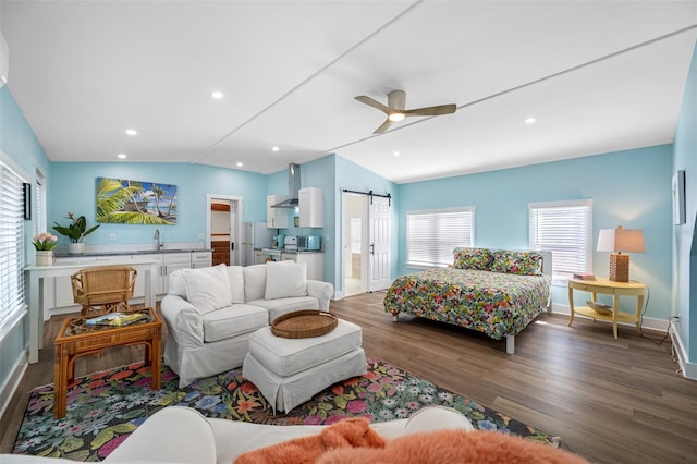 living room featuring hardwood / wood-style flooring, lofted ceiling, a barn door, and sink