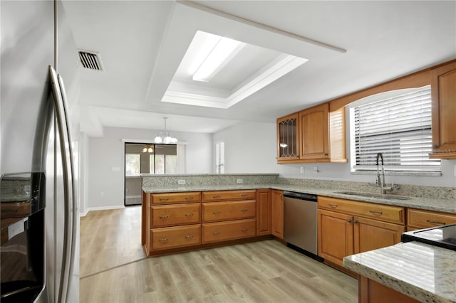 kitchen with sink, hanging light fixtures, a raised ceiling, kitchen peninsula, and stainless steel appliances