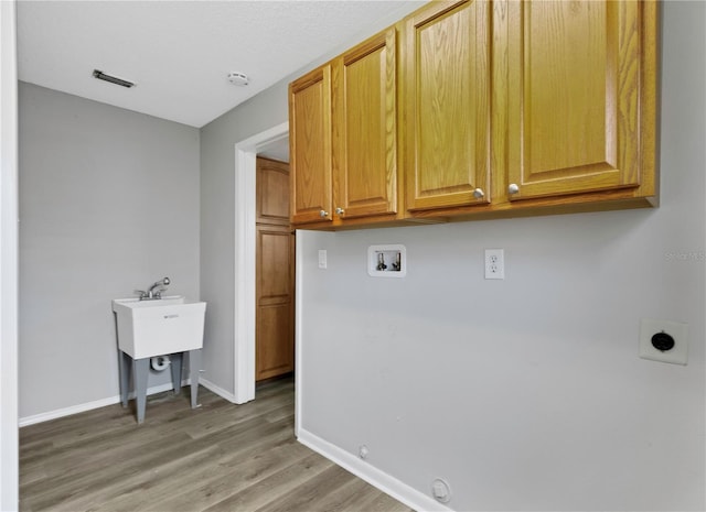 laundry area featuring gas dryer hookup, wood-type flooring, cabinets, washer hookup, and electric dryer hookup