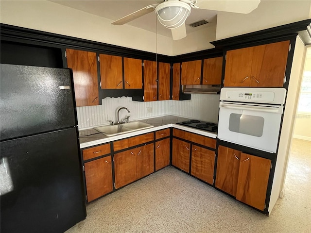 kitchen featuring white oven, black fridge, sink, ceiling fan, and electric stovetop