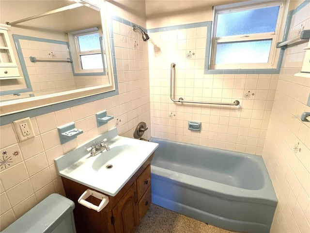 full bathroom featuring toilet, vanity, tiled shower / bath combo, and tile walls