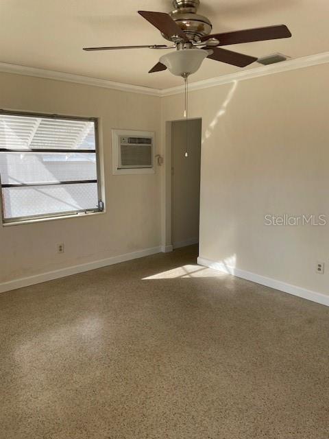 unfurnished room with ceiling fan, an AC wall unit, and crown molding