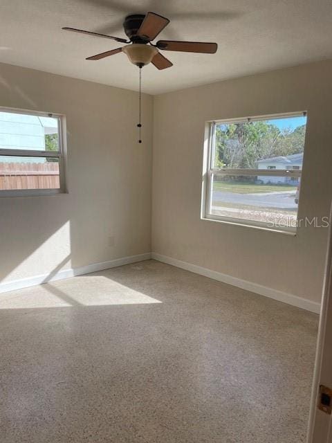 empty room with ceiling fan, plenty of natural light, and carpet