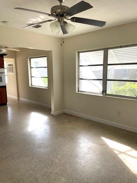 empty room featuring ceiling fan and a wealth of natural light