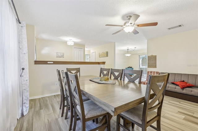 dining room with ceiling fan, a textured ceiling, and light wood-type flooring