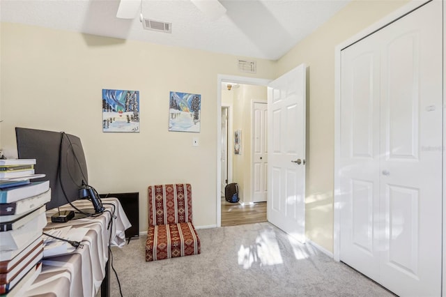 carpeted home office featuring a textured ceiling and ceiling fan