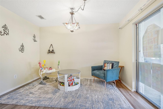 sitting room with a textured ceiling, light hardwood / wood-style floors, and a wealth of natural light