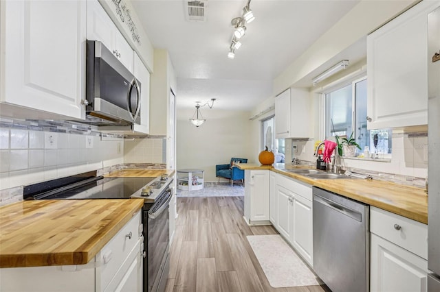 kitchen with stainless steel appliances, sink, light hardwood / wood-style flooring, white cabinets, and butcher block countertops