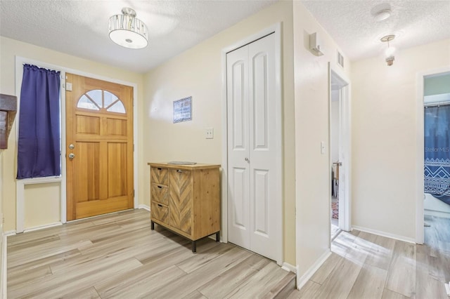 entrance foyer with light hardwood / wood-style floors and a textured ceiling