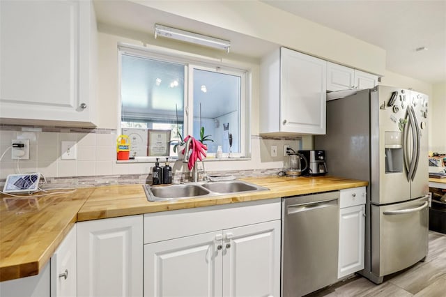 kitchen with white cabinets, light hardwood / wood-style flooring, stainless steel appliances, and wooden counters