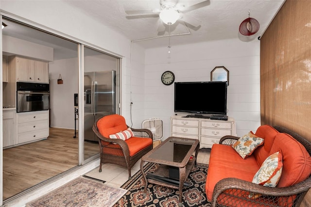 living room with a textured ceiling, light hardwood / wood-style flooring, and wooden walls