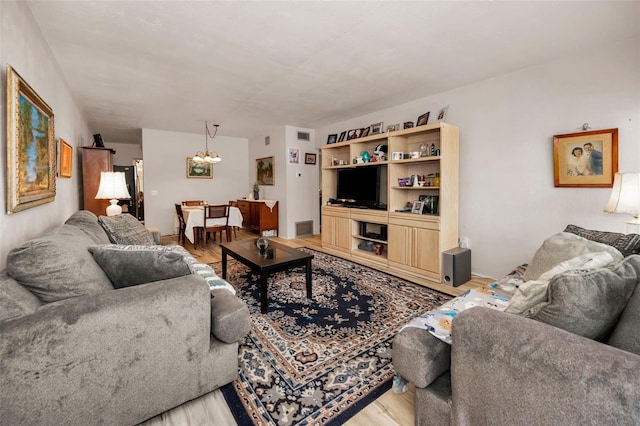 living area with an inviting chandelier, light wood-style flooring, and visible vents