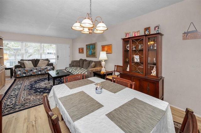 dining space featuring a notable chandelier, baseboards, and light wood-type flooring