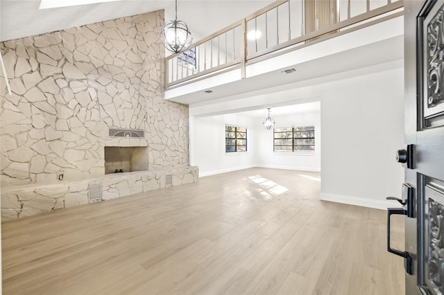 living room with a stone fireplace, hardwood / wood-style floors, high vaulted ceiling, and a chandelier