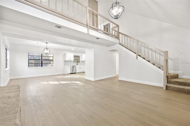 unfurnished living room with light hardwood / wood-style floors and a notable chandelier