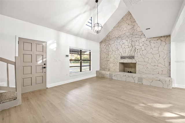 unfurnished living room featuring a fireplace, an inviting chandelier, high vaulted ceiling, and light hardwood / wood-style flooring