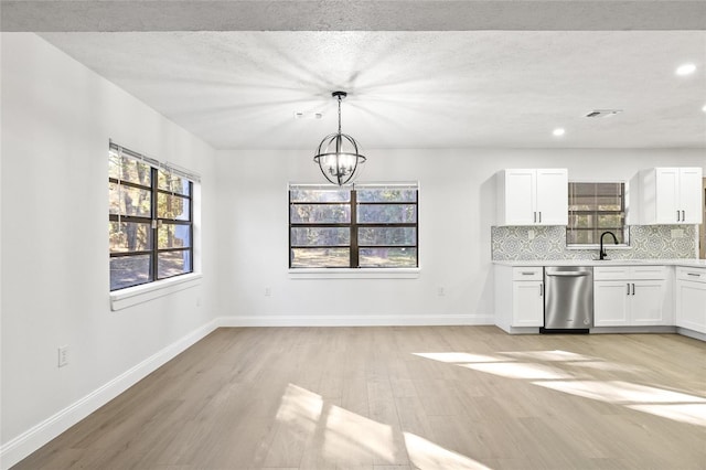 kitchen with white cabinets, light hardwood / wood-style flooring, a wealth of natural light, and stainless steel dishwasher