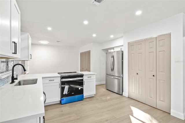 kitchen with decorative backsplash, appliances with stainless steel finishes, sink, white cabinets, and light hardwood / wood-style floors