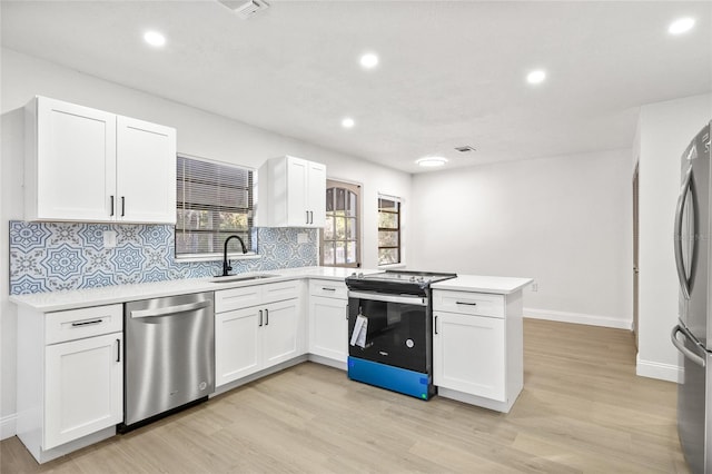 kitchen with white cabinets, sink, light wood-type flooring, kitchen peninsula, and stainless steel appliances