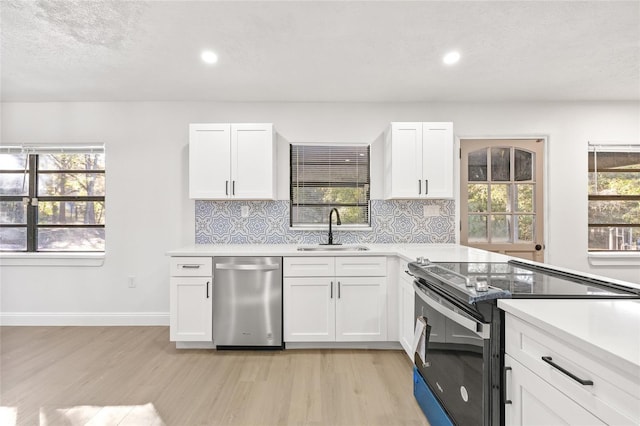 kitchen with black range with electric cooktop, white cabinetry, stainless steel dishwasher, and sink