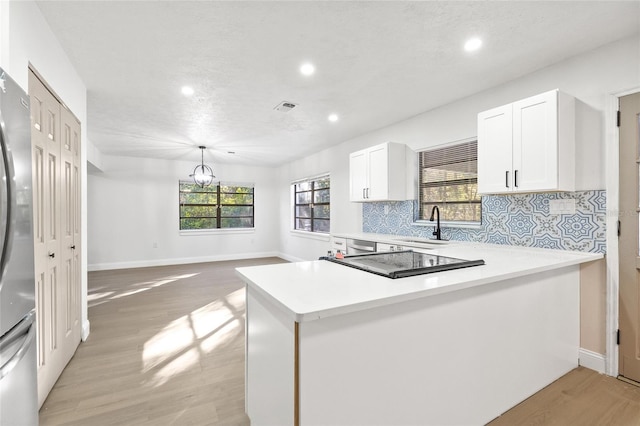 kitchen with decorative backsplash, light wood-type flooring, and a healthy amount of sunlight