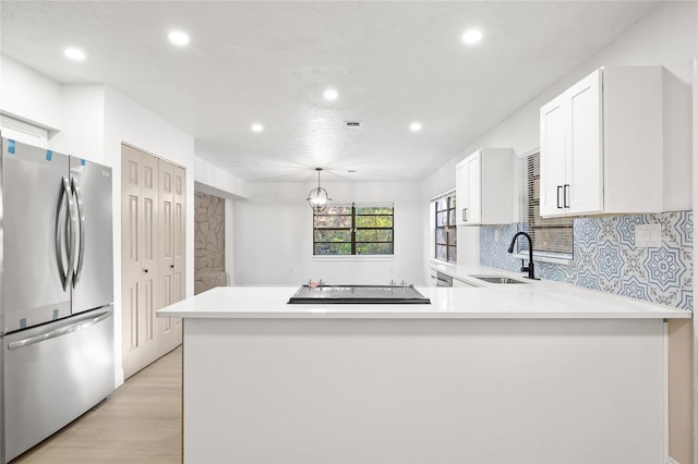 kitchen featuring stainless steel refrigerator, sink, light hardwood / wood-style flooring, kitchen peninsula, and white cabinets