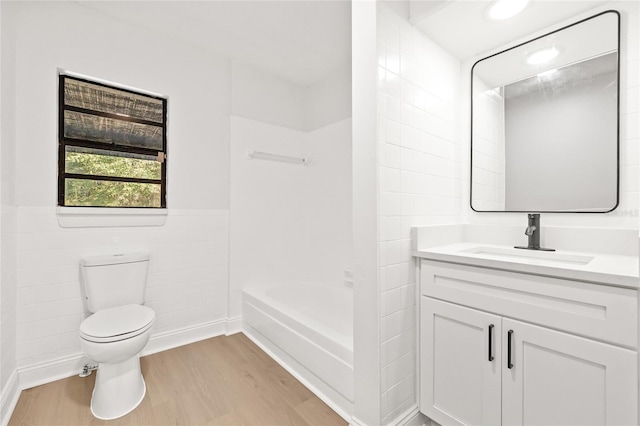 bathroom with vanity, hardwood / wood-style flooring, tile walls, toilet, and a bathing tub