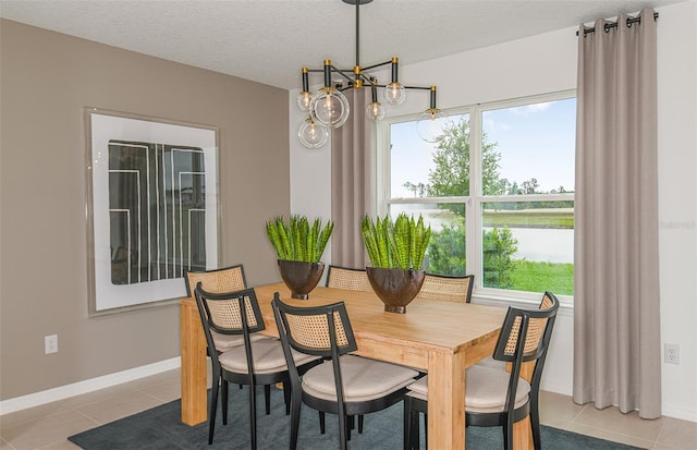 tiled dining space featuring a notable chandelier, a water view, and a textured ceiling