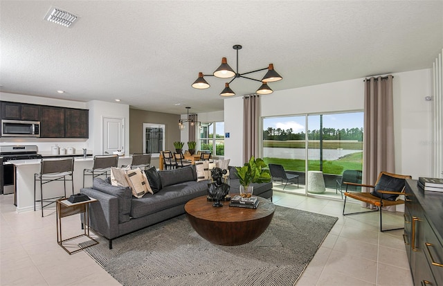 living room featuring light tile patterned flooring, a textured ceiling, and a chandelier