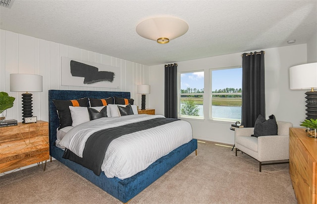 carpeted bedroom featuring a textured ceiling and a water view