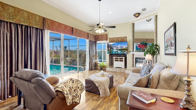 living room with light hardwood / wood-style floors, ceiling fan, and ornamental molding