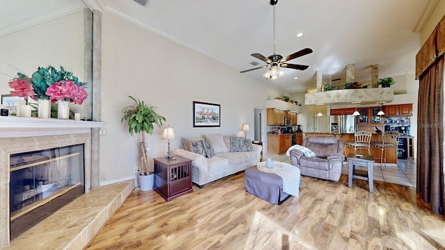 living room featuring high vaulted ceiling, crown molding, ceiling fan, light wood-type flooring, and a fireplace