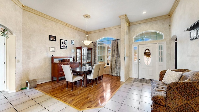 dining room featuring a towering ceiling, light hardwood / wood-style floors, and ornamental molding