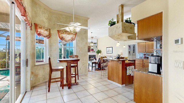 kitchen with a kitchen breakfast bar, ceiling fan, a center island, and light tile patterned flooring