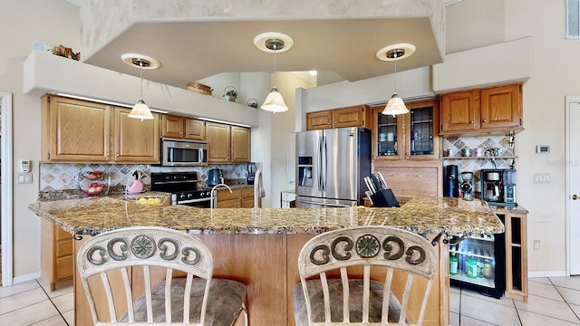 kitchen featuring decorative backsplash, light tile patterned floors, a breakfast bar area, and appliances with stainless steel finishes