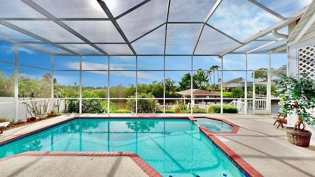 view of pool with glass enclosure and a patio area