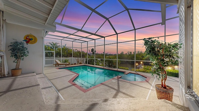 pool at dusk featuring a patio and glass enclosure