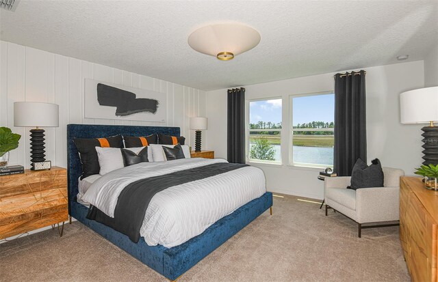 bedroom featuring a textured ceiling, a water view, and light colored carpet