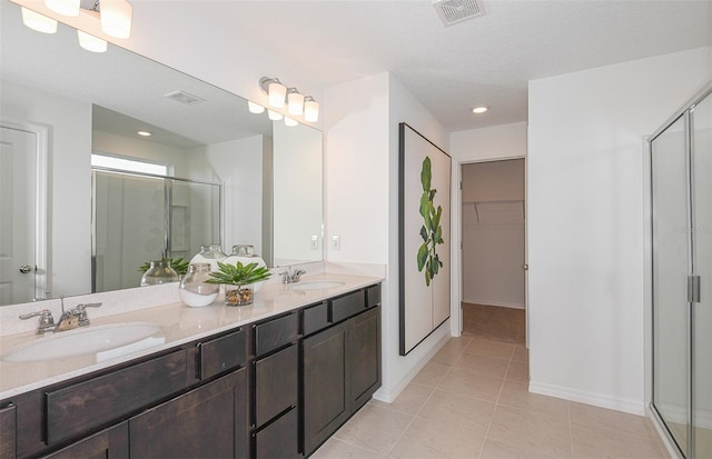 bathroom with tile patterned flooring, a textured ceiling, vanity, and walk in shower