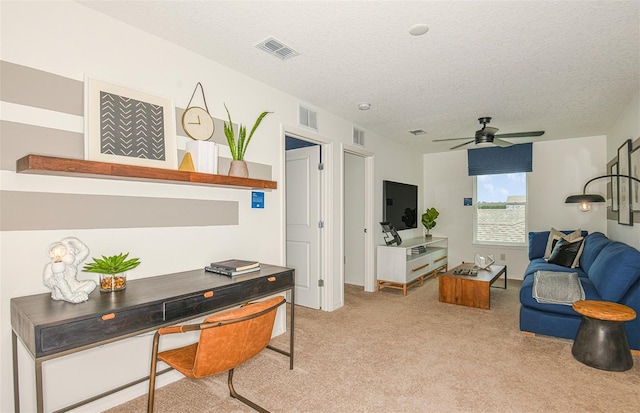 office space with light carpet, a textured ceiling, and ceiling fan