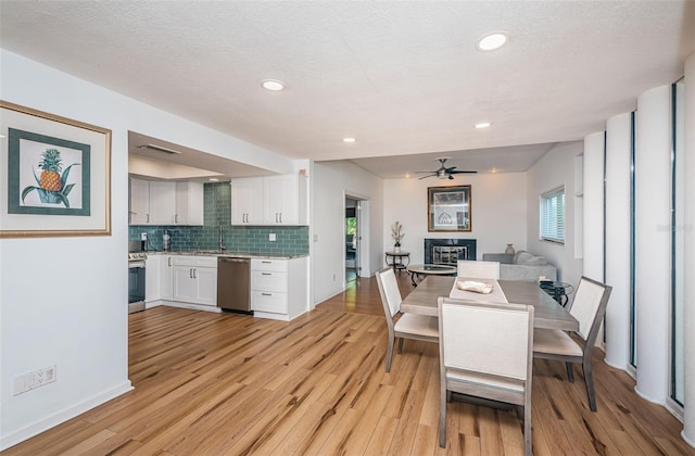 dining room featuring ceiling fan, light wood-type flooring, and a textured ceiling