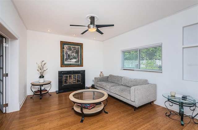 living room featuring hardwood / wood-style floors, ceiling fan, and ornamental molding