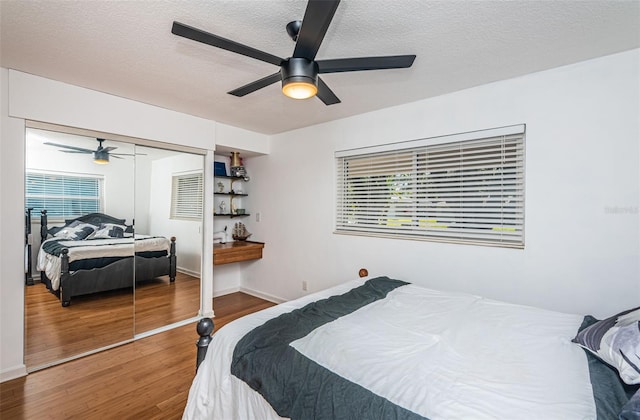 bedroom featuring multiple windows, ceiling fan, a closet, and wood-type flooring