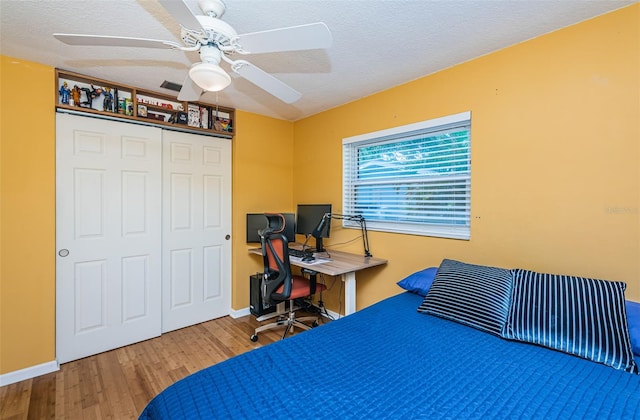 bedroom with wood-type flooring, a textured ceiling, a closet, and ceiling fan