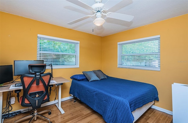 bedroom featuring ceiling fan, wood-type flooring, and a textured ceiling