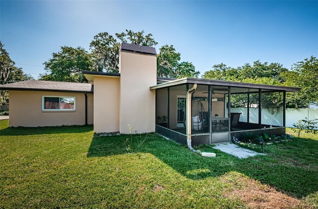 rear view of house with a lawn and a sunroom