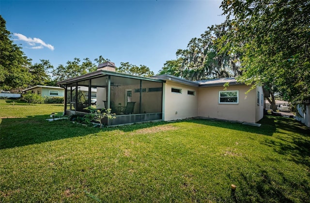 back of property featuring a sunroom and a lawn