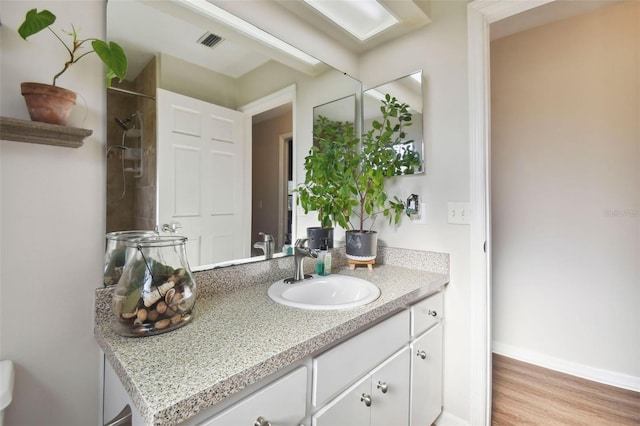 bathroom with a shower, hardwood / wood-style floors, and vanity