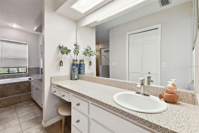 bathroom featuring tile patterned floors, vanity, and tiled tub