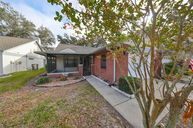 view of front of home featuring a sunroom, central AC unit, and a front lawn